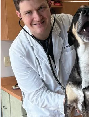 Dr. Alex Bischoff smiling with a dog in the exam room